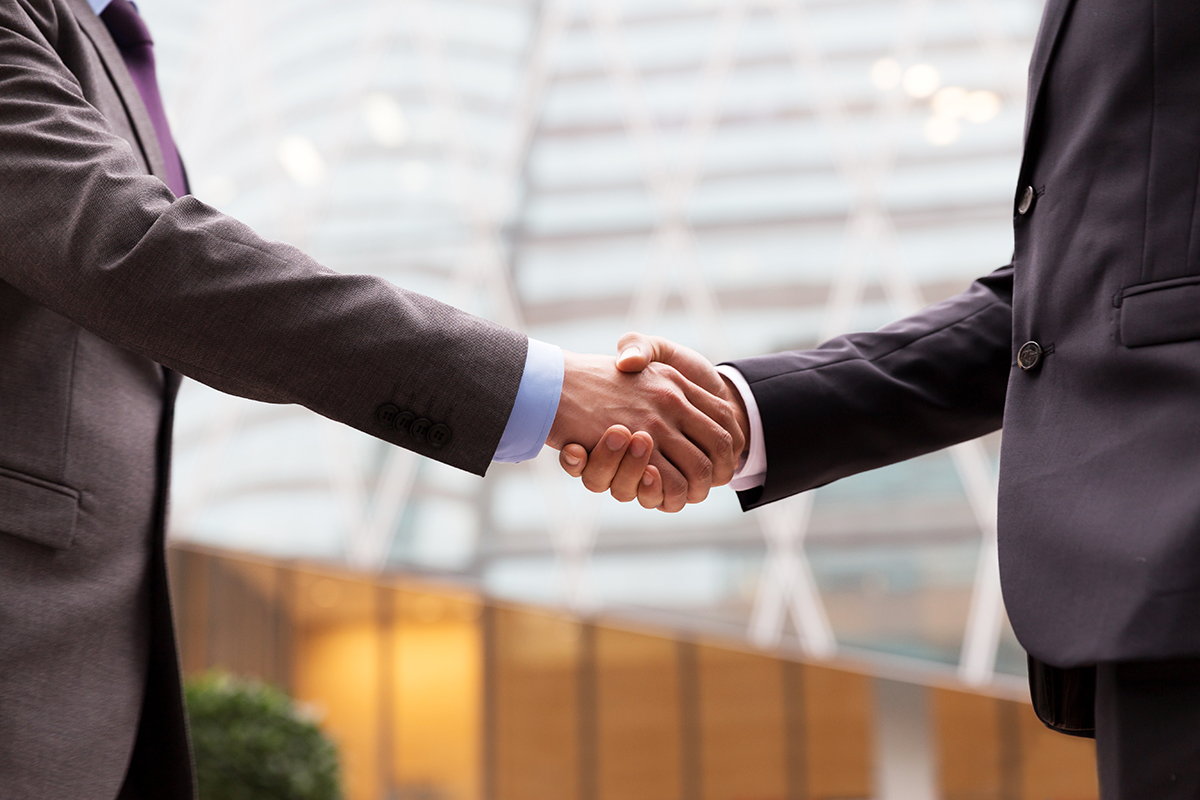 An image of two people wearing suits and shaking hands.